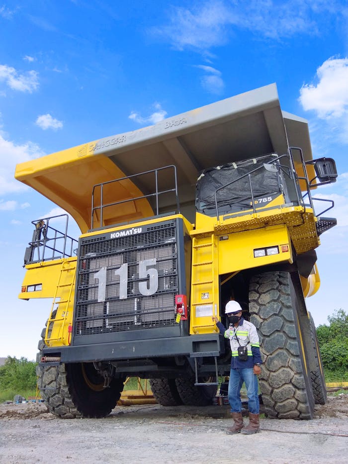 hero-img-01 A large Komatsu mining truck with a worker standing beside it in Indonesia.