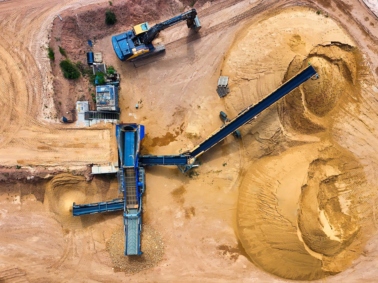 services-02 Top view of sand mining machinery and piles in outdoor quarry.